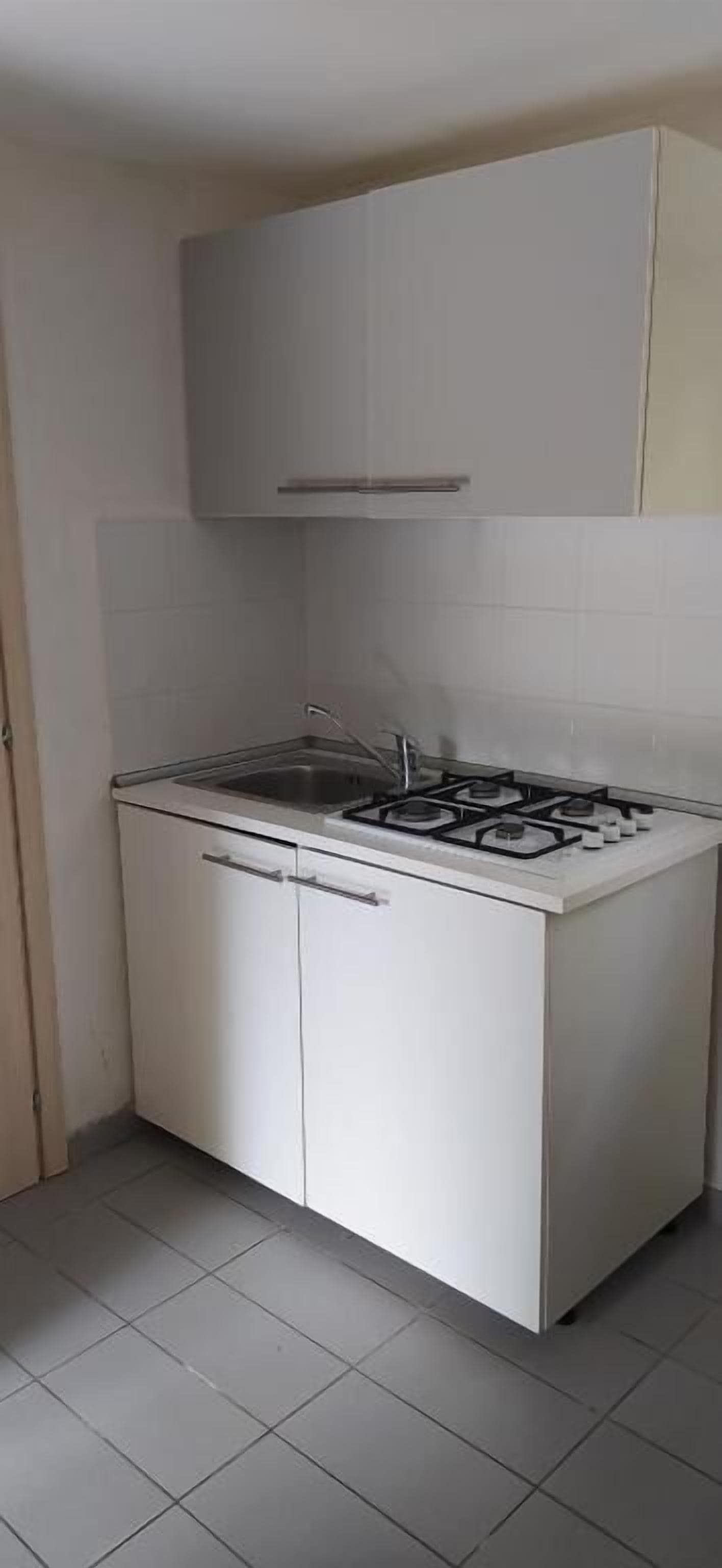 A compact kitchen with white cabinets, a gas stove, and a tiled backsplash.