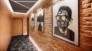 Een gang met een bakstenen muur en kunstwerken in lijsten.