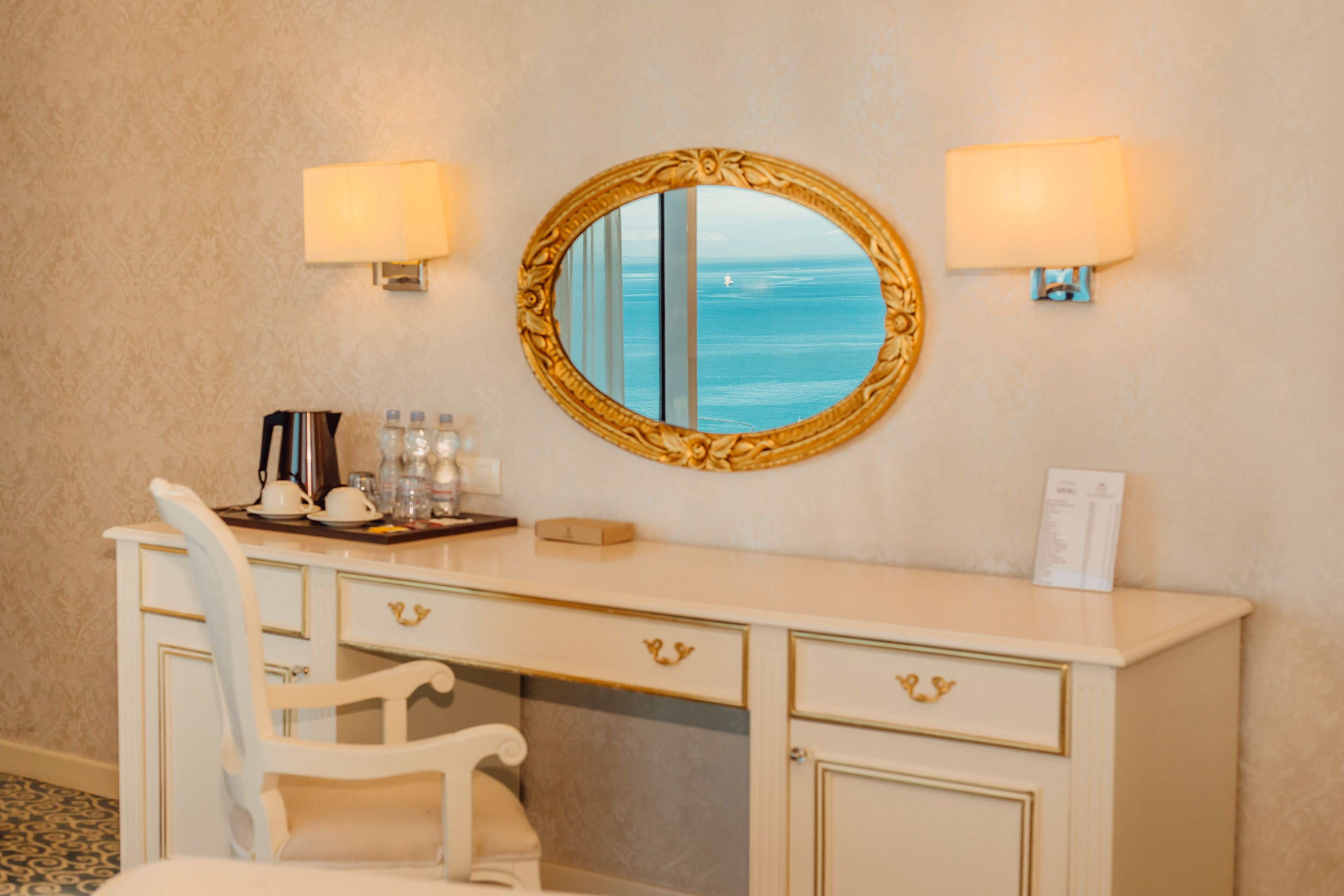 Habitación con escritorio, silla y un gran espejo con vista al mar.