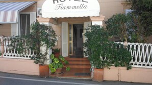 Un hôtel appelé « HOTEL Fiammella », doté d’une entrée accueillante, de plantes en pot et d’une clôture blanche décorative.
