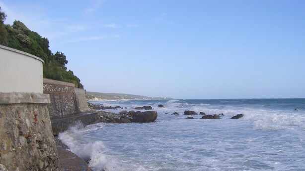 Un paysage côtier avec un mur de pierre et une plage rocheuse.