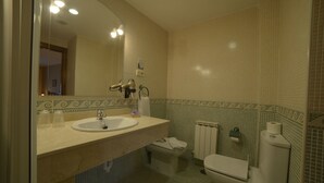 Un baño con lavamanos, espejo, inodoro y radiador.