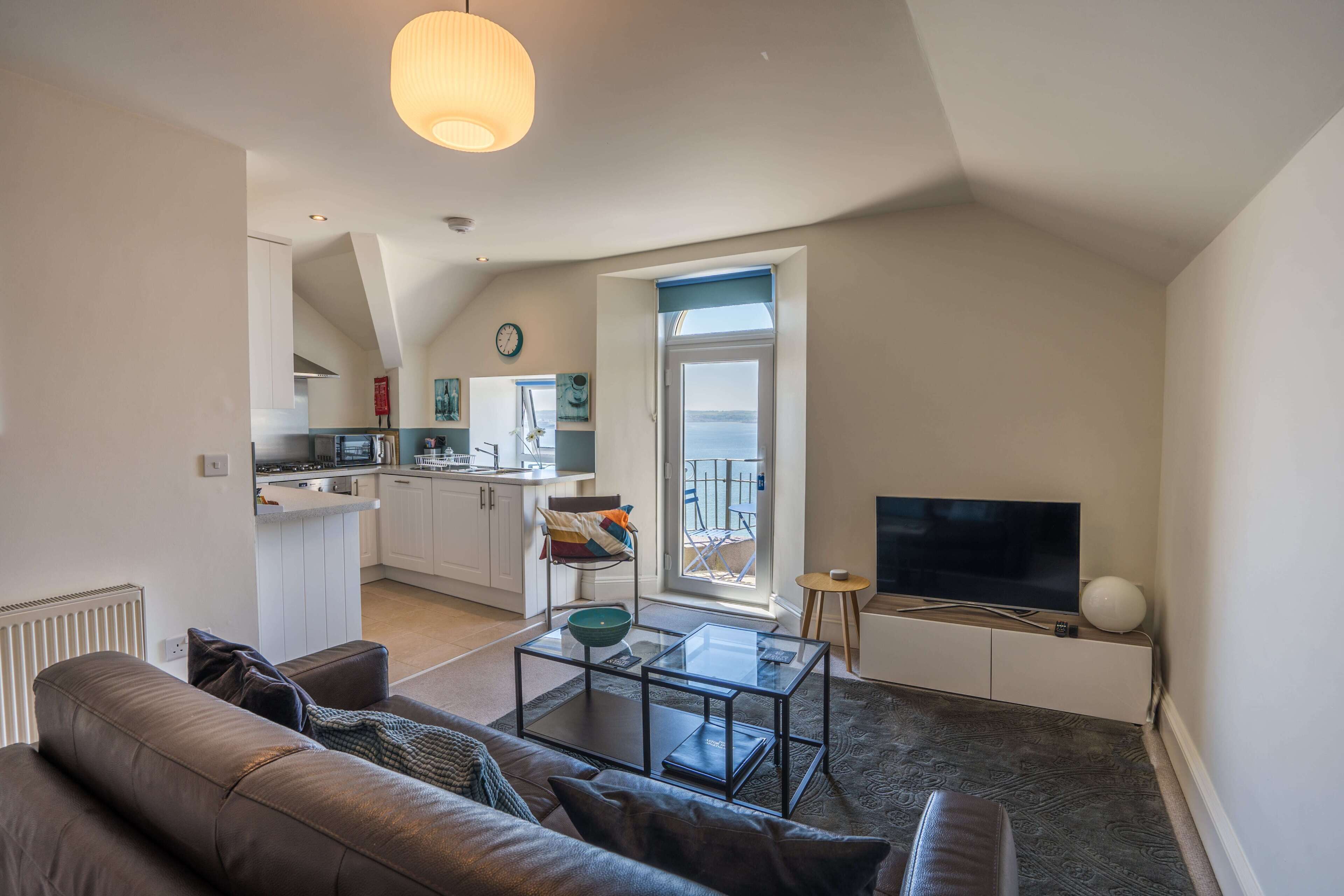 A modern apartment with a living room, kitchen, and balcony.