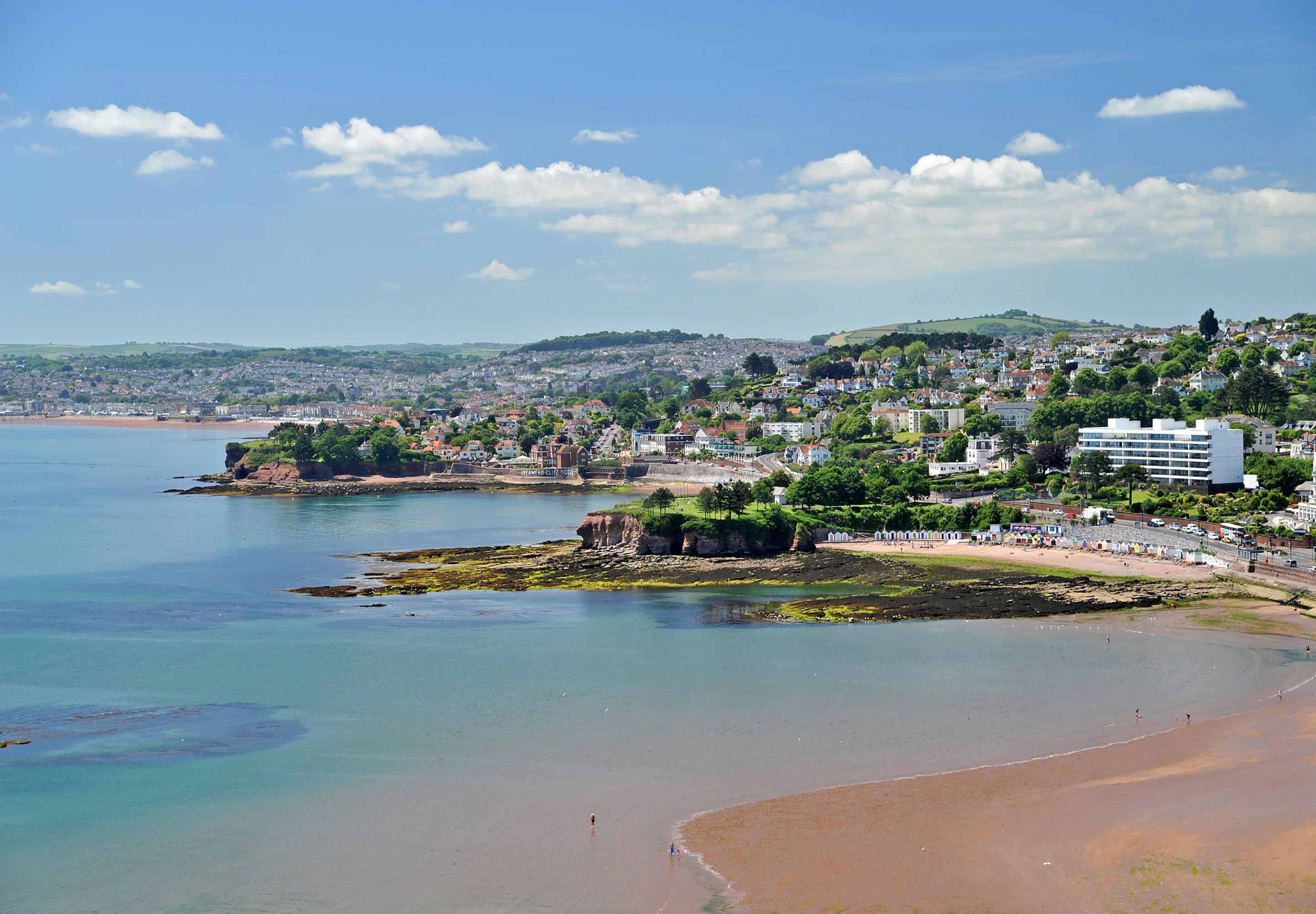 A coastal town with a beach, buildings, and a clear sky.