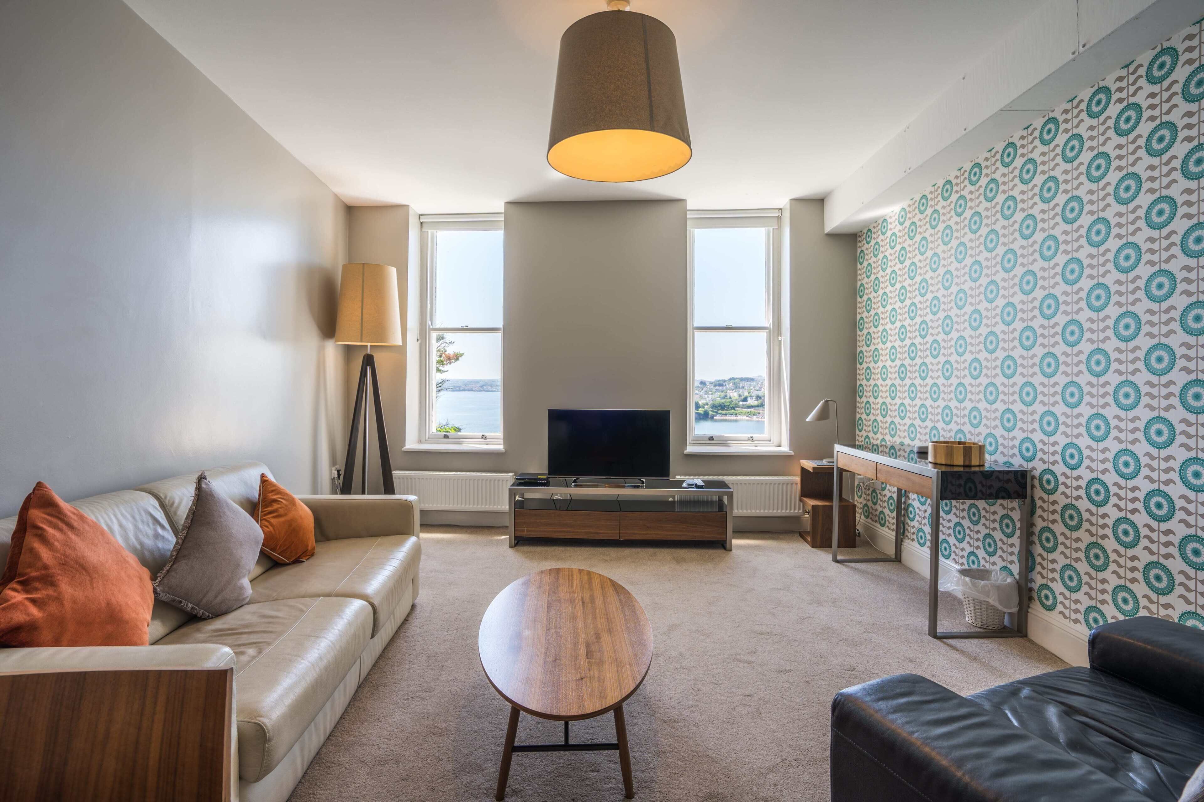 A modern living room with a sofa, a round coffee table, and a television on a wooden cabinet.