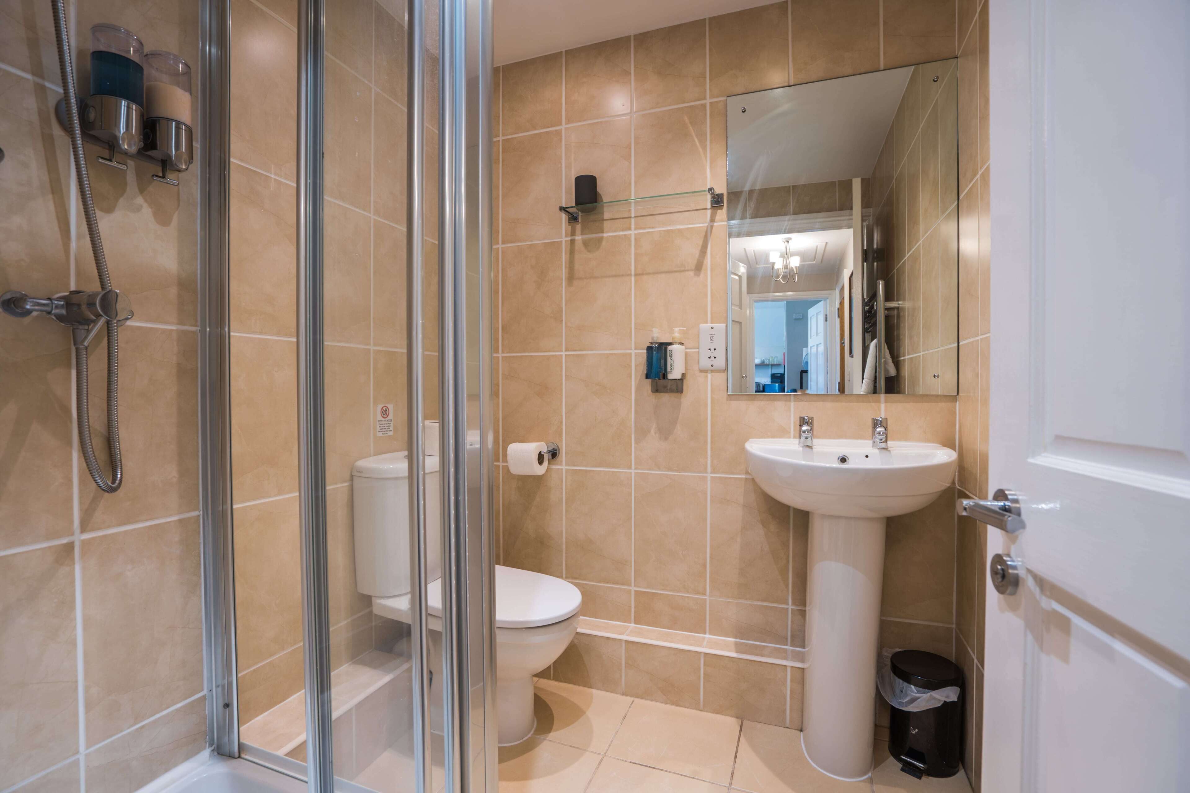 Ein modernes Badezimmer mit Duschkabine aus Glas, Toilette, Waschbecken und Spiegel.