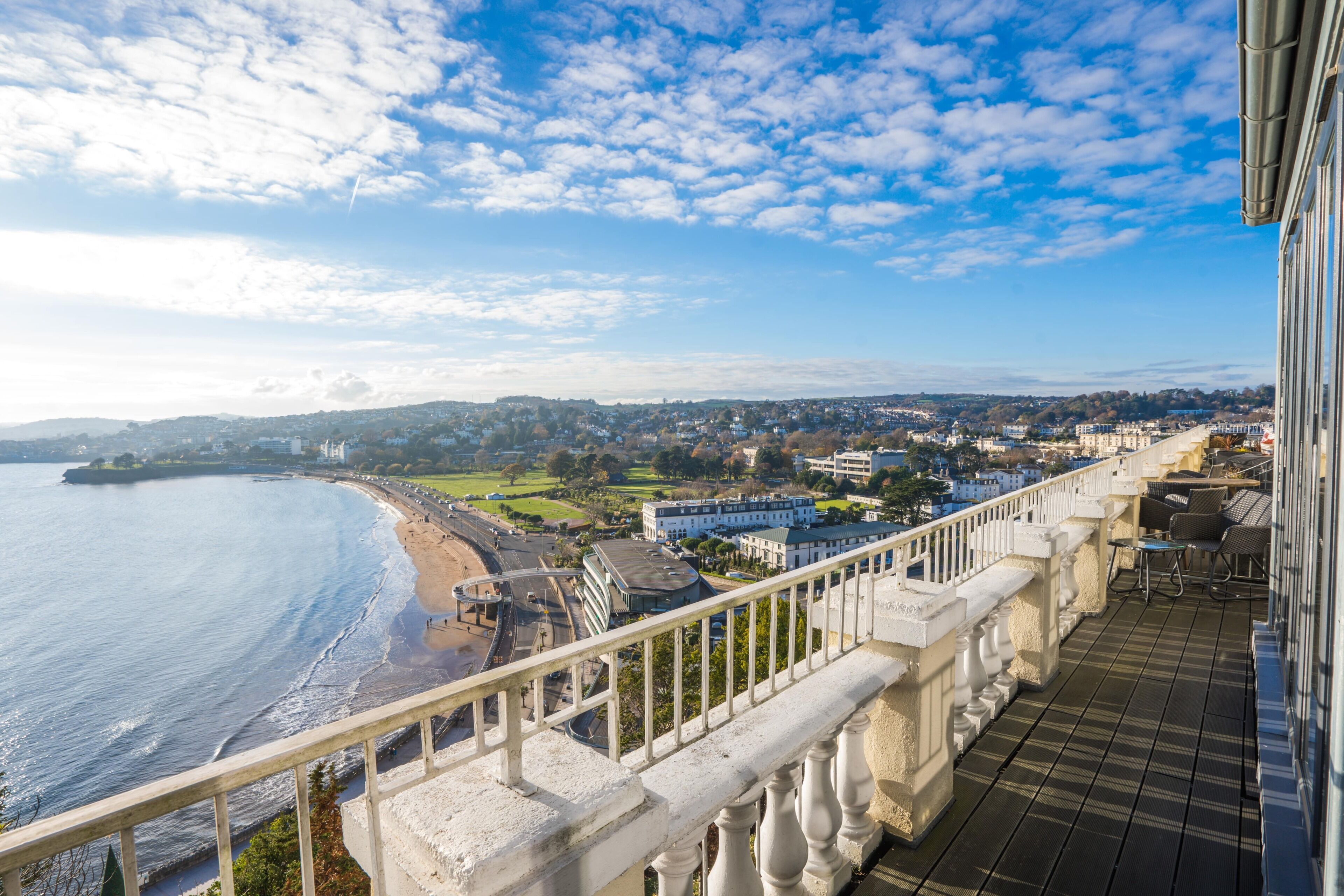 A balcony with a view of a beach and cityscape.