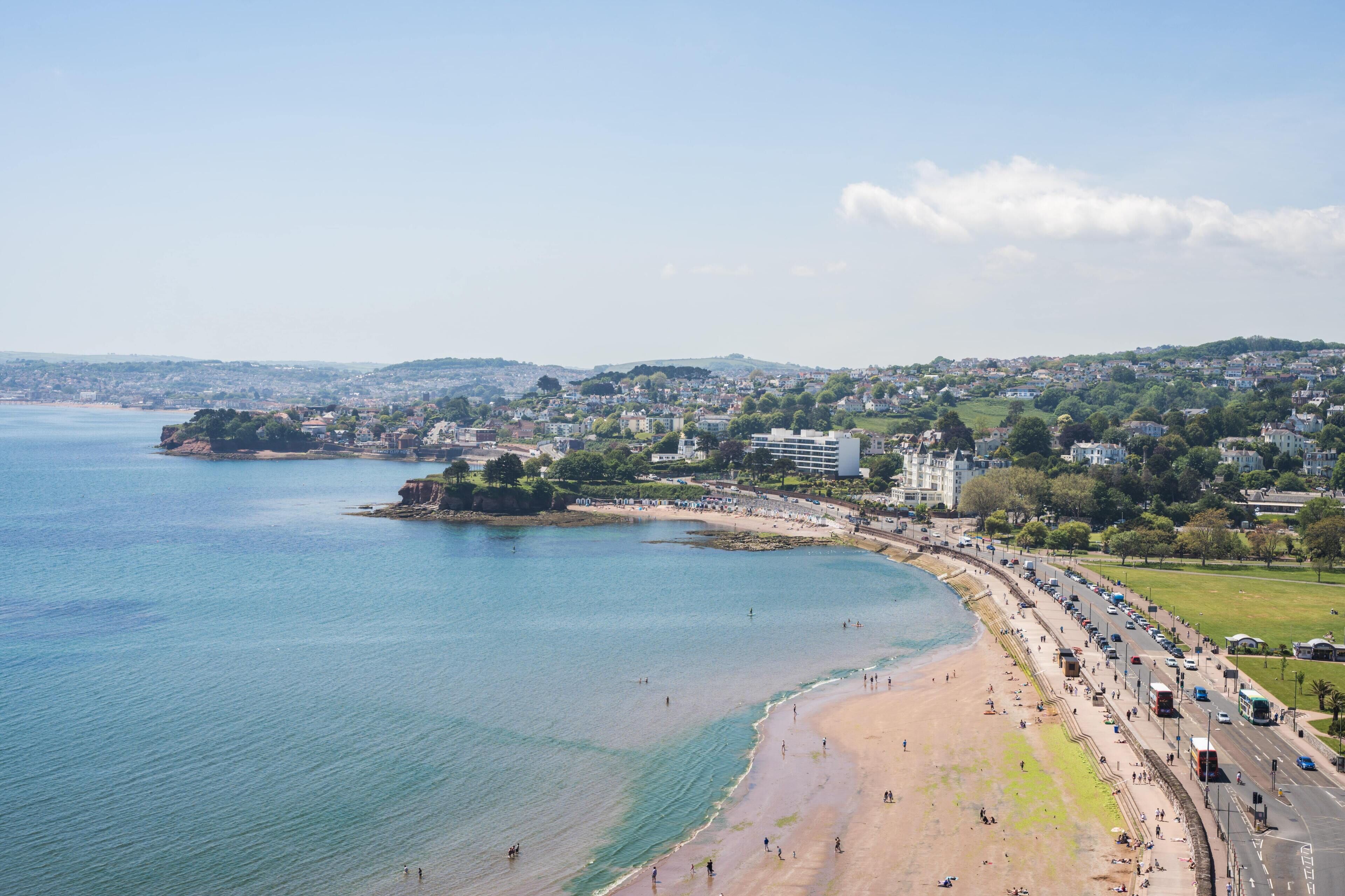 Paisatge urbà costaner amb platja, passeig marítim i edificis al fons.