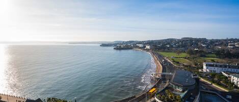A coastal town with a beach, a curved road, and buildings along the shore.