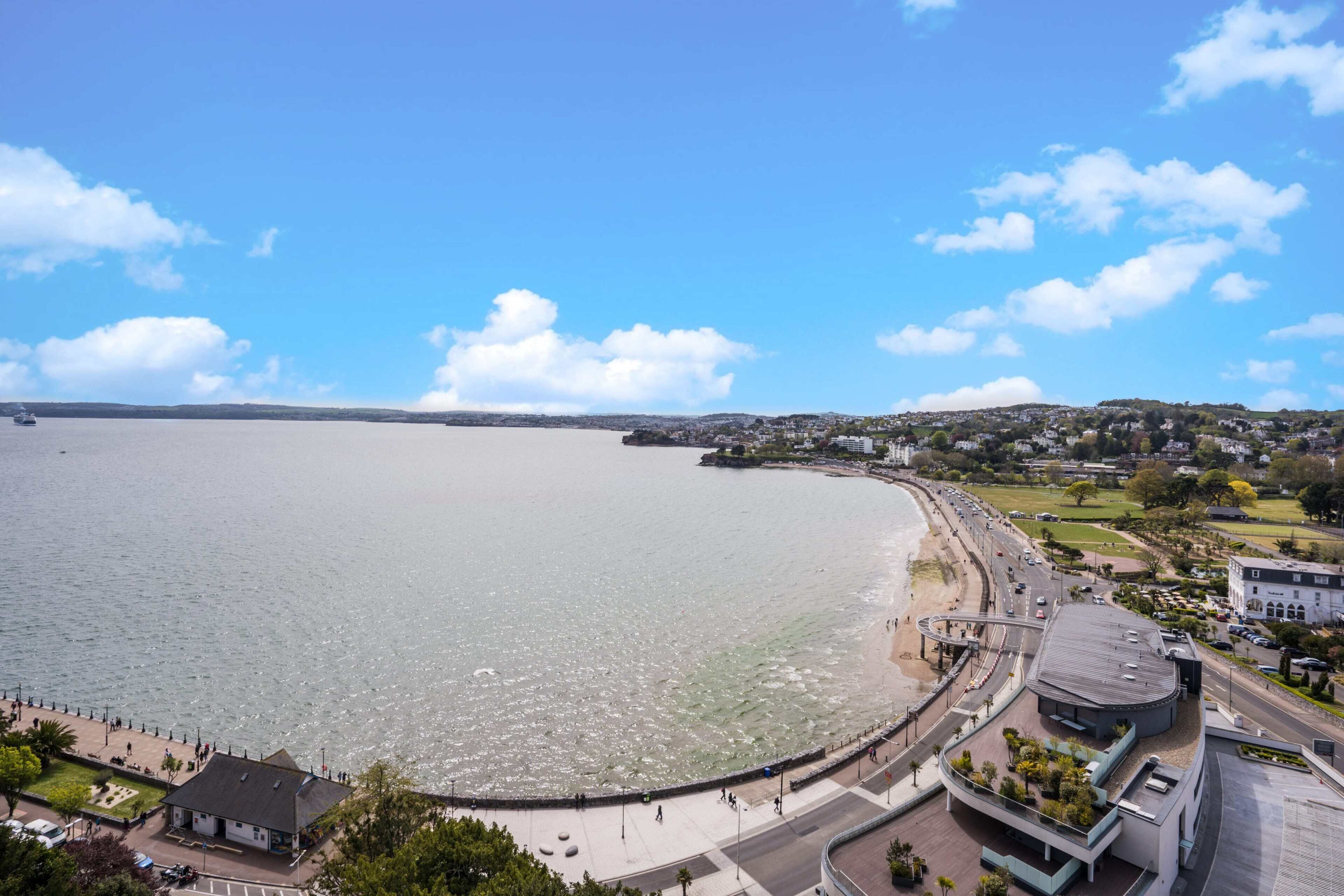 Une vue sur la côte, avec une promenade, des bâtiments et un ciel dégagé.