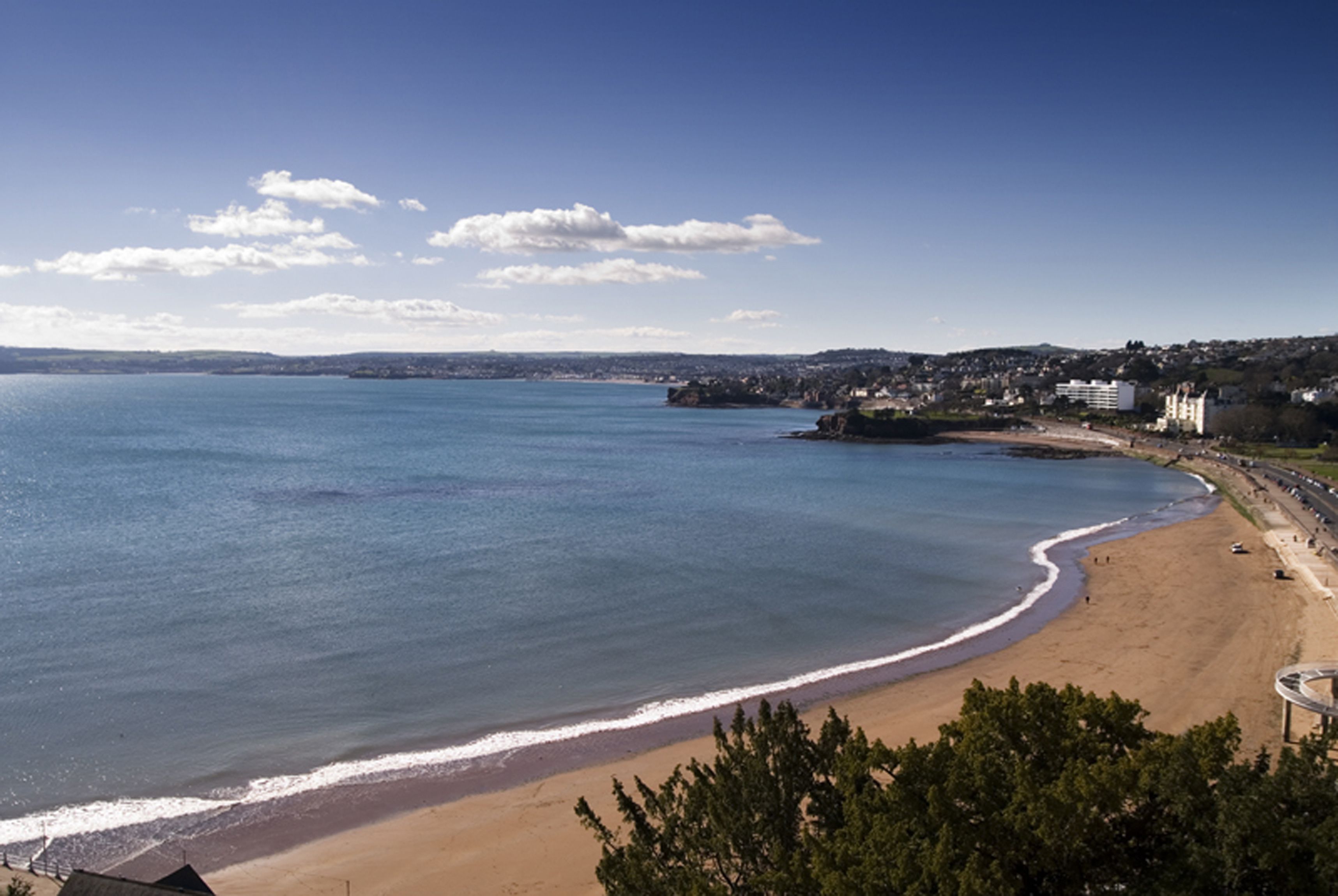 A coastal beach with a clear view of the sea and a sandy shore.