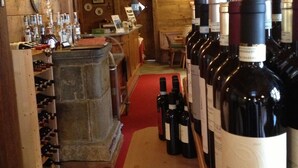 Une cave à vin avec des poutres en bois, un comptoir en pierre et des rangées de bouteilles de vin.