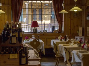 Un restaurante con interiores de madera, mesas dispuestas para comer y botellas de vino exhibidas en la barra.