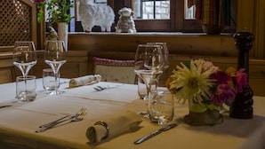 Une table à manger dressée avec des verres à vin, des couverts et un centre de table composé de fleurs.