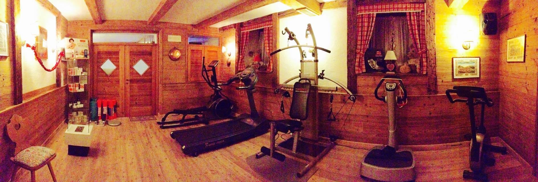 Ein Fitnessraum mit Trainingsgeräten, Holzwänden und einer kleinen Sitzecke.