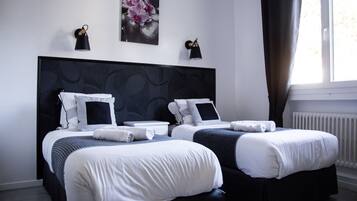 Ein Hotelzimmer mit zwei Betten, einem großen abstrakten Gemälde und zwei Wandleuchten.