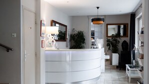 A modern bathroom with a curved vanity, a large mirror, and a potted plant.