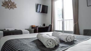 A hotel room with a bed, a desk, a chair, a television, and a window with curtains.