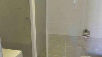 Een badkamer met een douchecabine, een toilet en een wastafel.