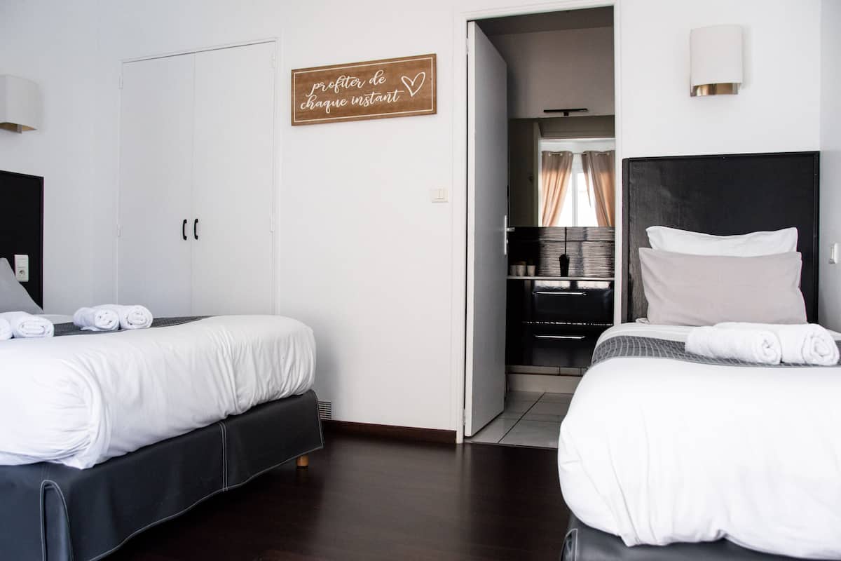 A hotel room with two beds, a wardrobe, a mirror, and a sign on the wall.