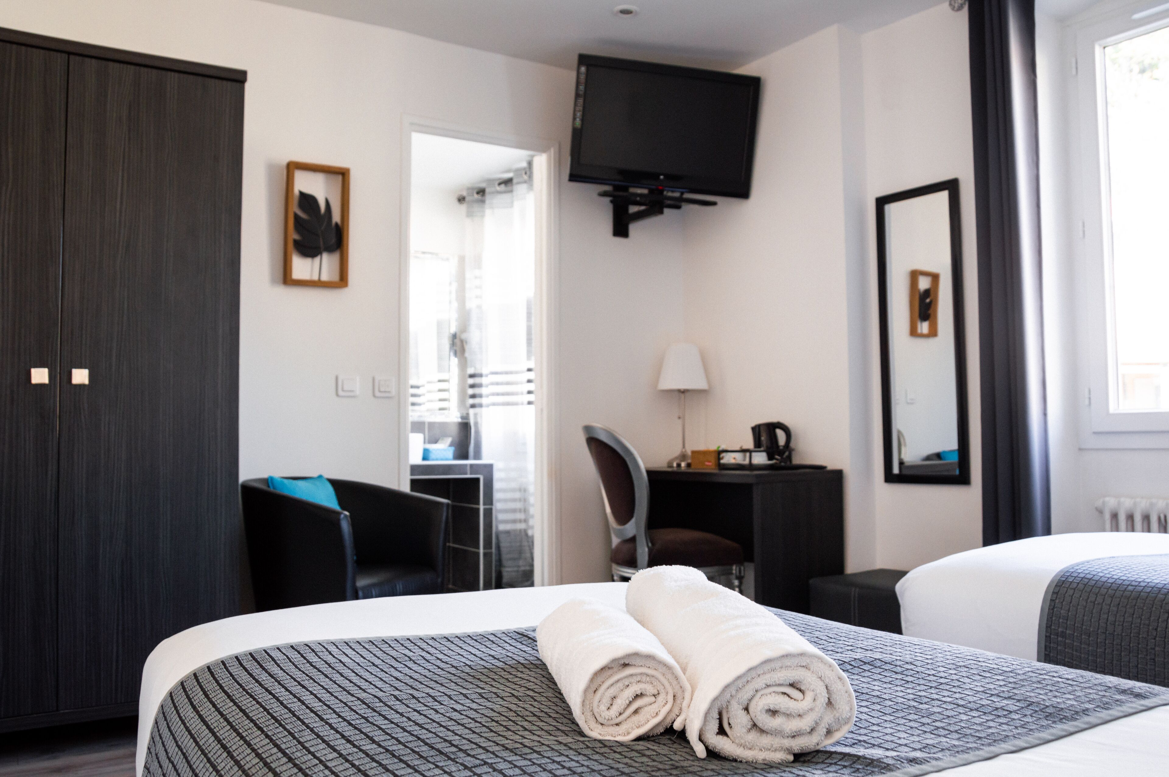 Une chambre d’hôtel avec deux lits, un bureau, une chaise, une télévision et une armoire.