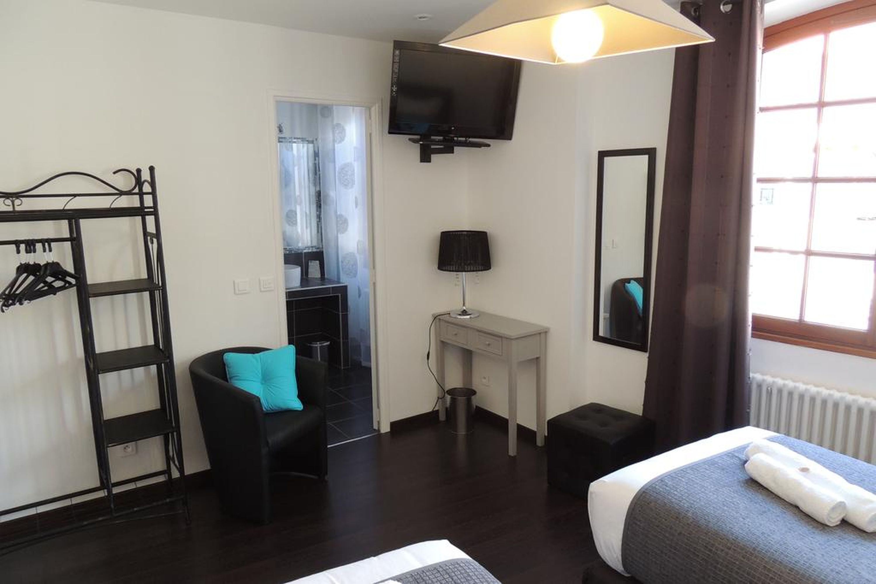 A hotel room with a bed, a desk, a chair, a TV, a wardrobe, and a window.