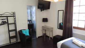 A hotel room with a bed, a desk, a chair, a TV, a wardrobe, and a window.