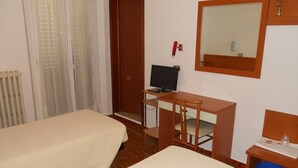 Habitación de hotel con dos camas, un escritorio con computadora, un espejo y una mesita con lámpara.