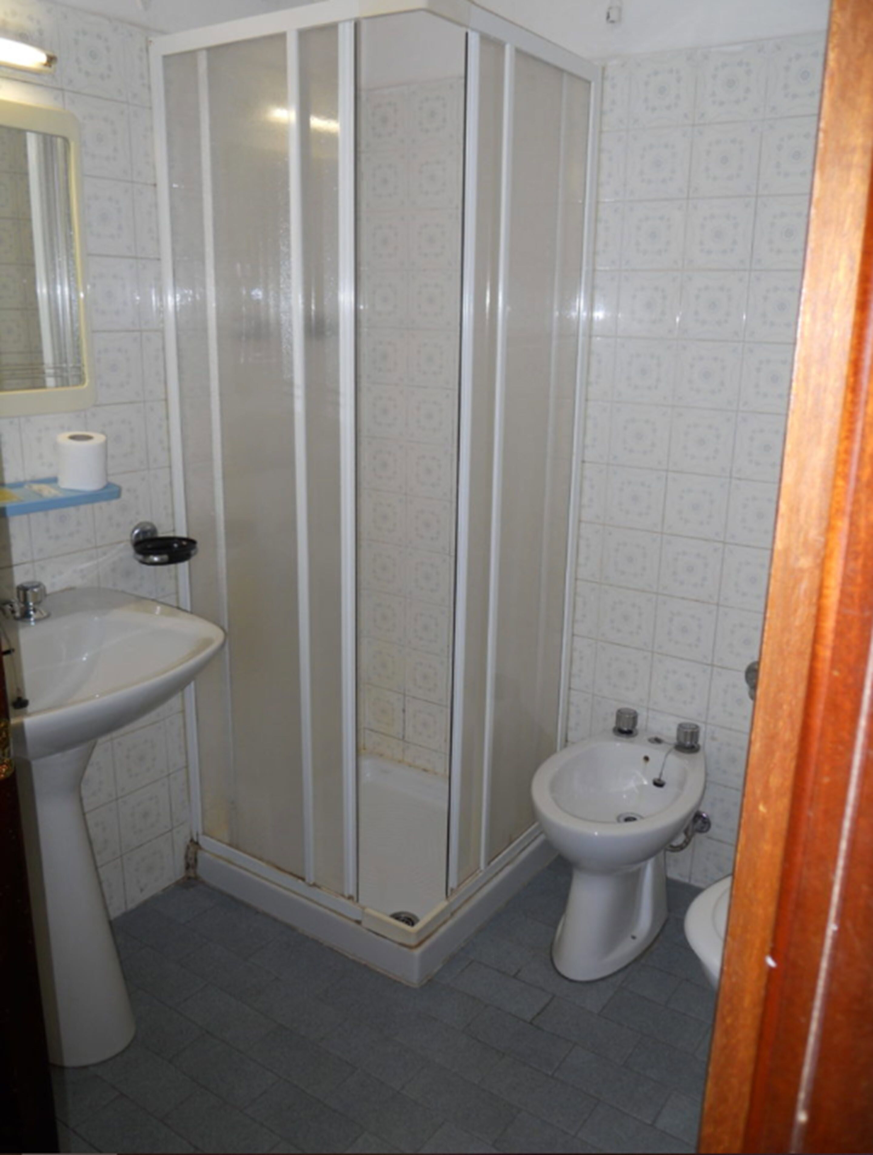 A bathroom with a shower enclosure, a sink, and a bidet.