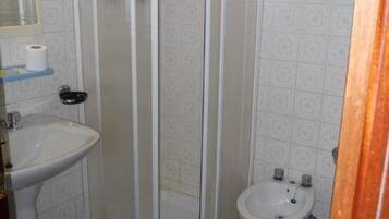 A bathroom with a shower enclosure, a sink, and a bidet.