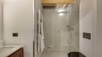 A modern bathroom with a glass-enclosed shower, a toilet, and a towel rack.