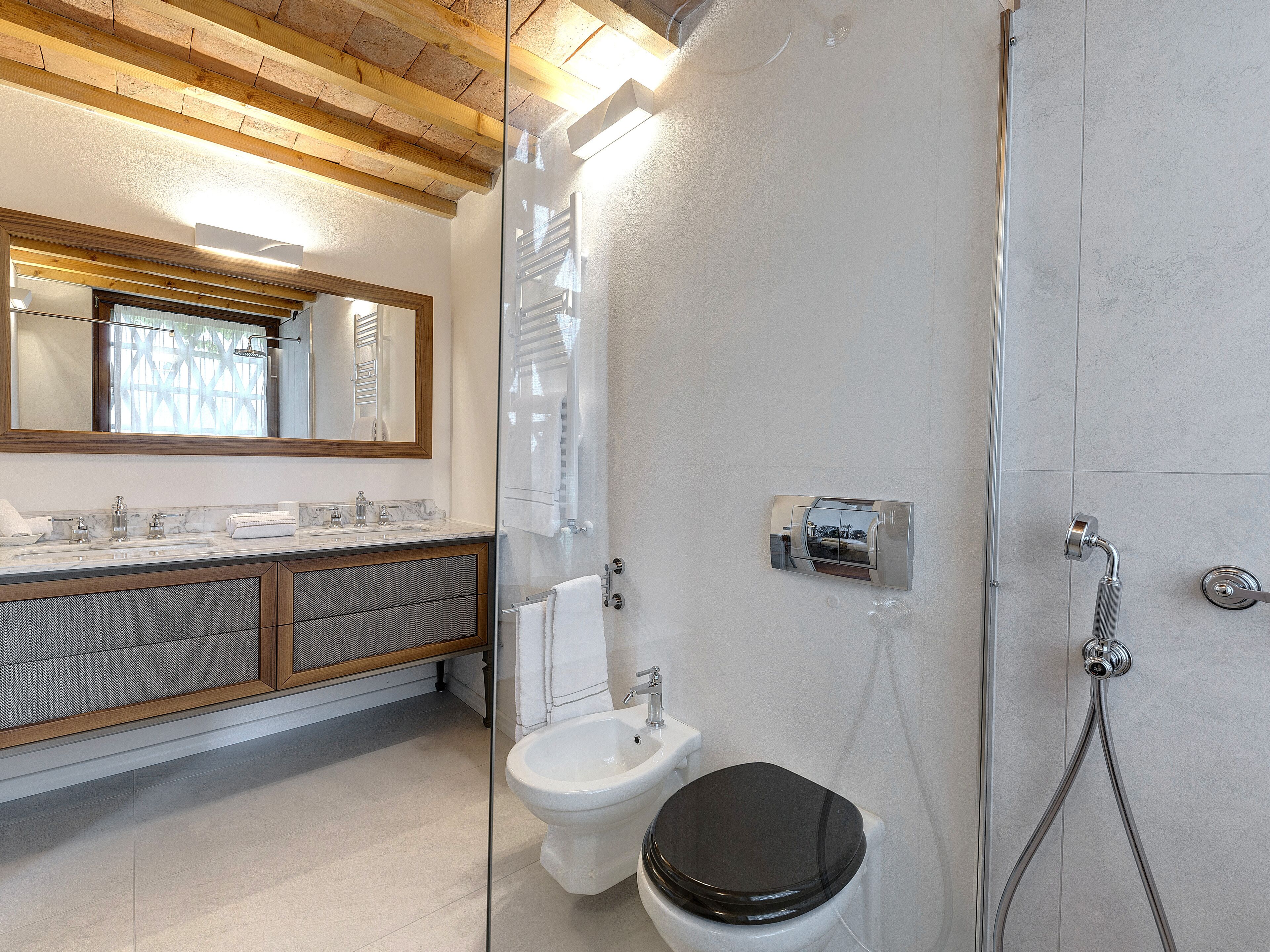 A modern bathroom with a glass shower enclosure, a toilet, and a vanity with a mirror.