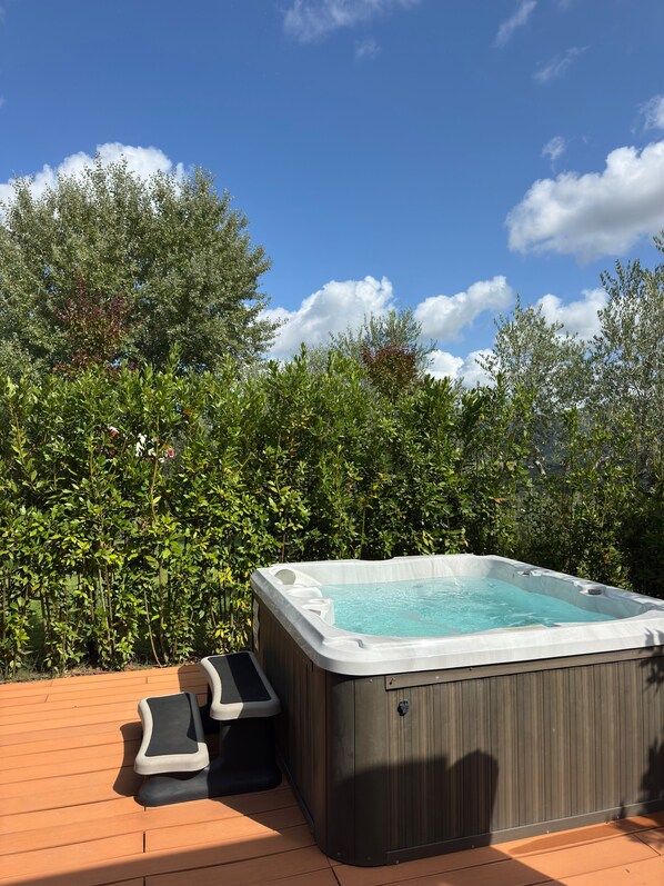 A hot tub on a wooden deck with a view of lush greenery and a clear blue sky. - Terre di Baccio (Greve in Chianti)