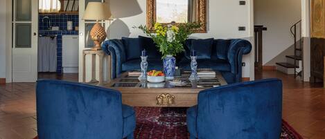 Un salon avec un canapé bleu, une table basse agrémentée d’objets décoratifs et un tapis à motifs.