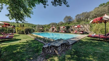 Una piscina al aire libre de temporada, sombrillas