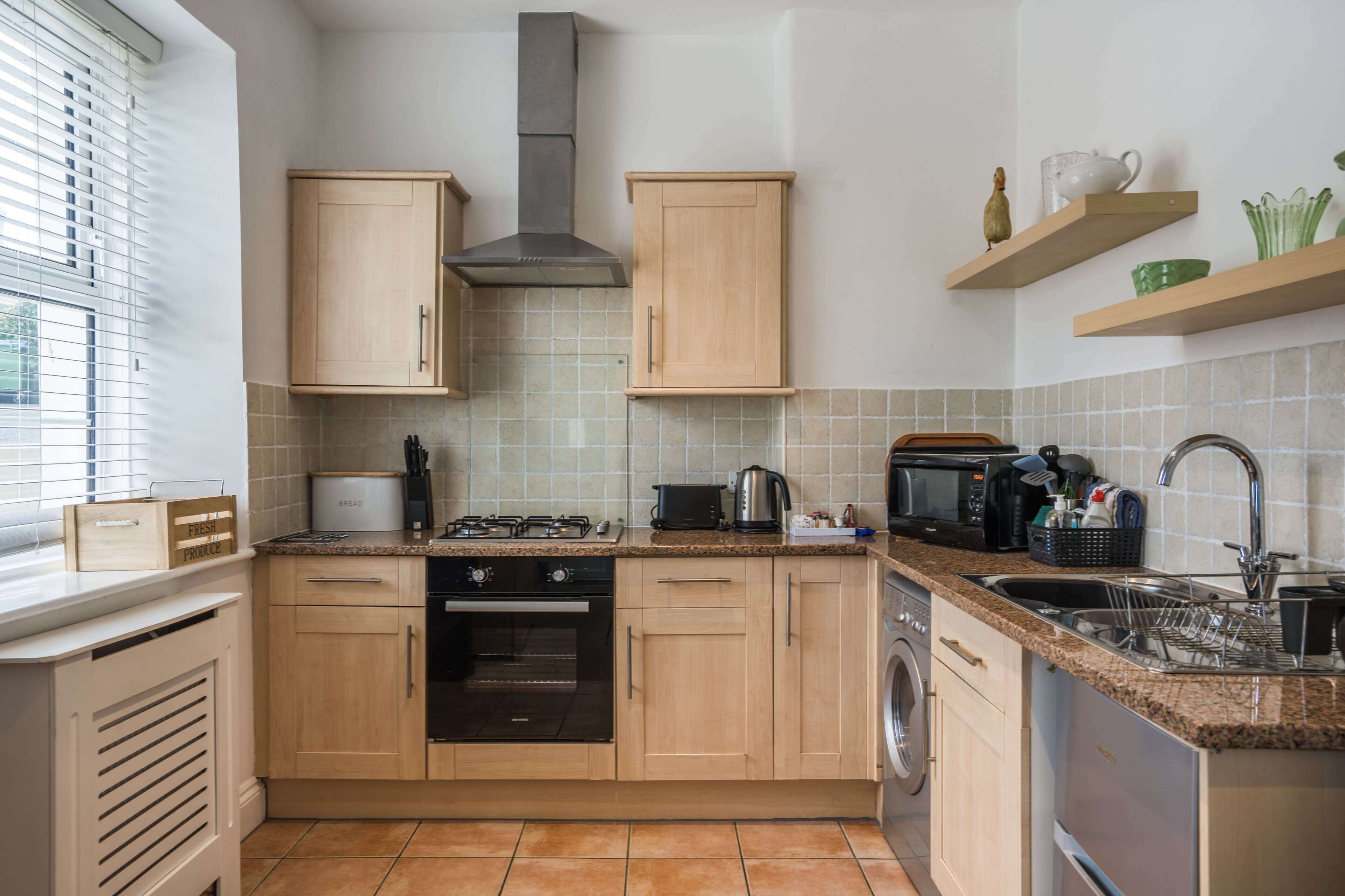 A modern kitchen with wooden cabinets, a gas stove, an oven, a microwave, and a dishwasher.