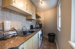 A compact kitchen with a built-in oven, a sink, and a washing machine.