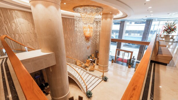Eine geräumige Lobby mit einer imposanten Treppe, großen Säulen und einem Kronleuchter.