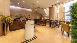 Ein modernes Café-Interieur mit einer Rezeption, einer Sitzgelegenheit und einer Treppe, die in einen oberen Bereich führt.