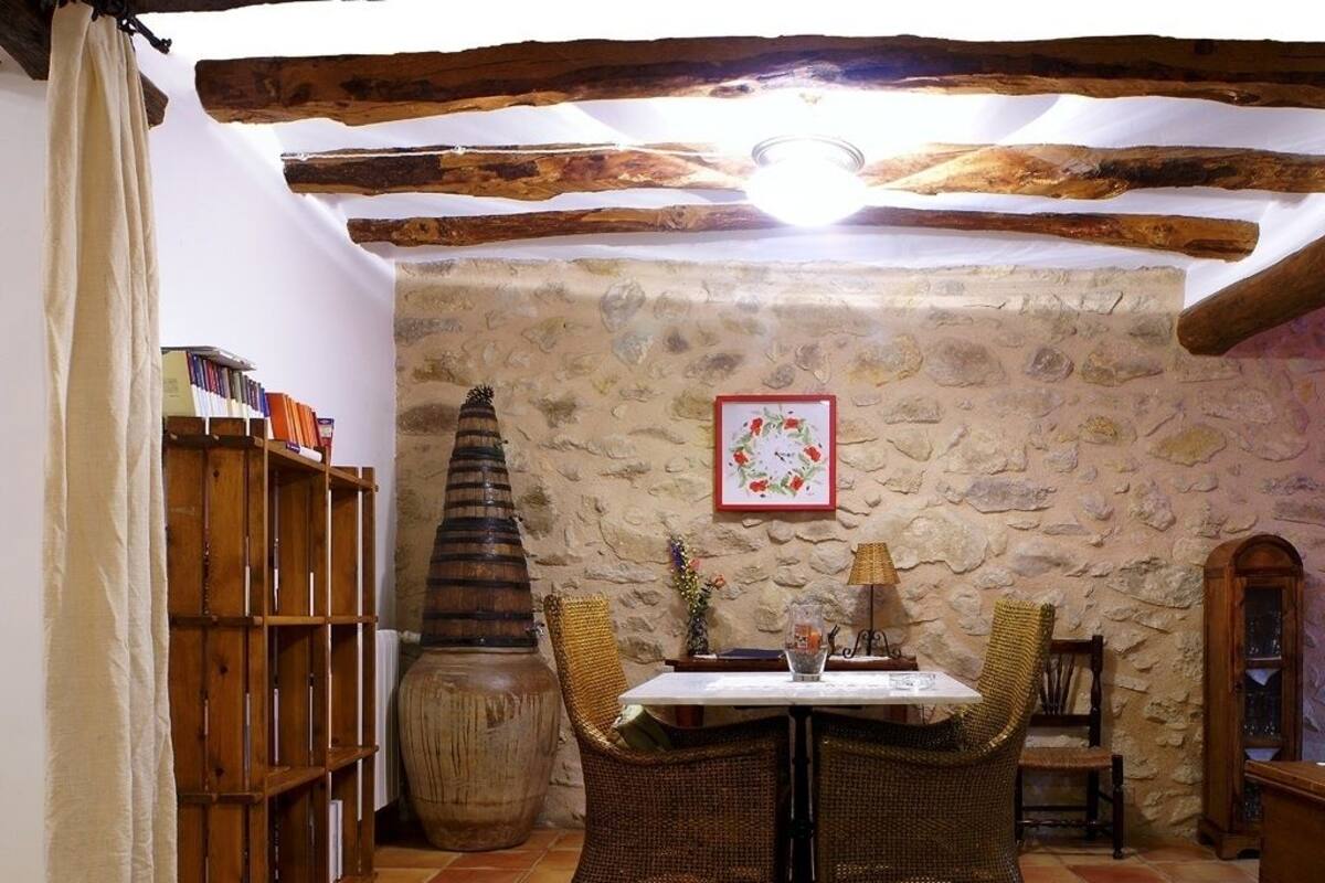 A rustic dining area with a stone wall, wooden furniture, and a bookshelf.