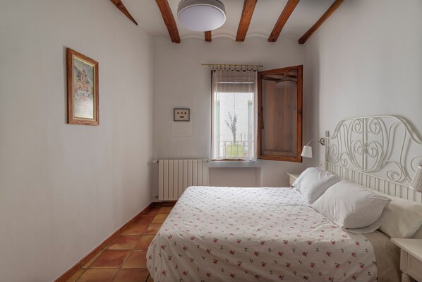A bedroom with a bed, a window with curtains, a radiator, and a picture on the wall. - La Llar d´Aitana (Alcoleja)