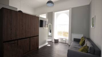 A modern living room with a grey sofa, a wooden cabinet, and a small round table.