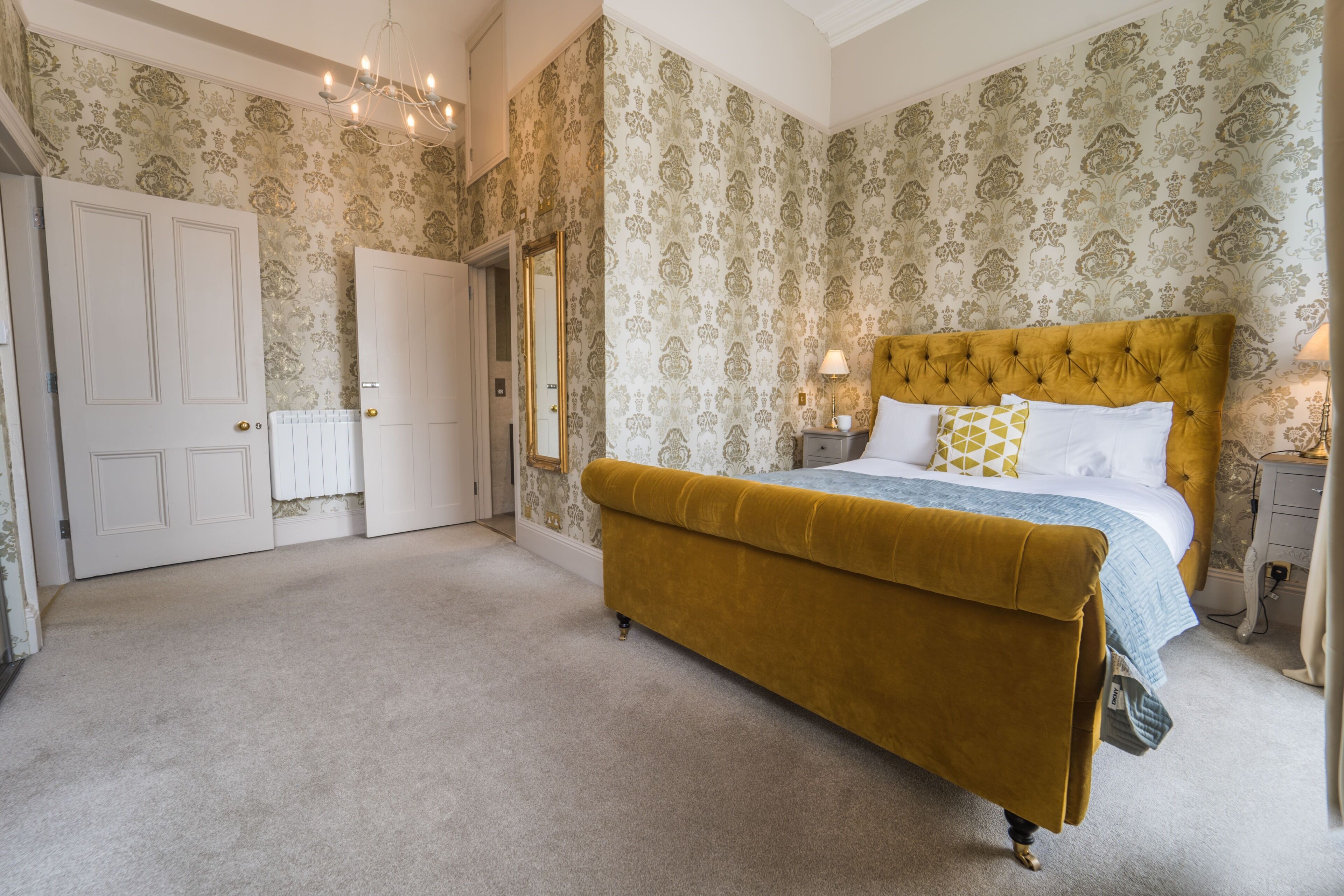 A bedroom with a large bed, a wardrobe, and a mirror.