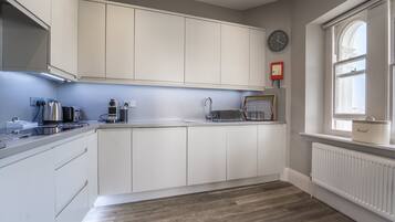 Una cocina moderna con armarios blancos, horno empotrado, cafetera y ventana con vistas.