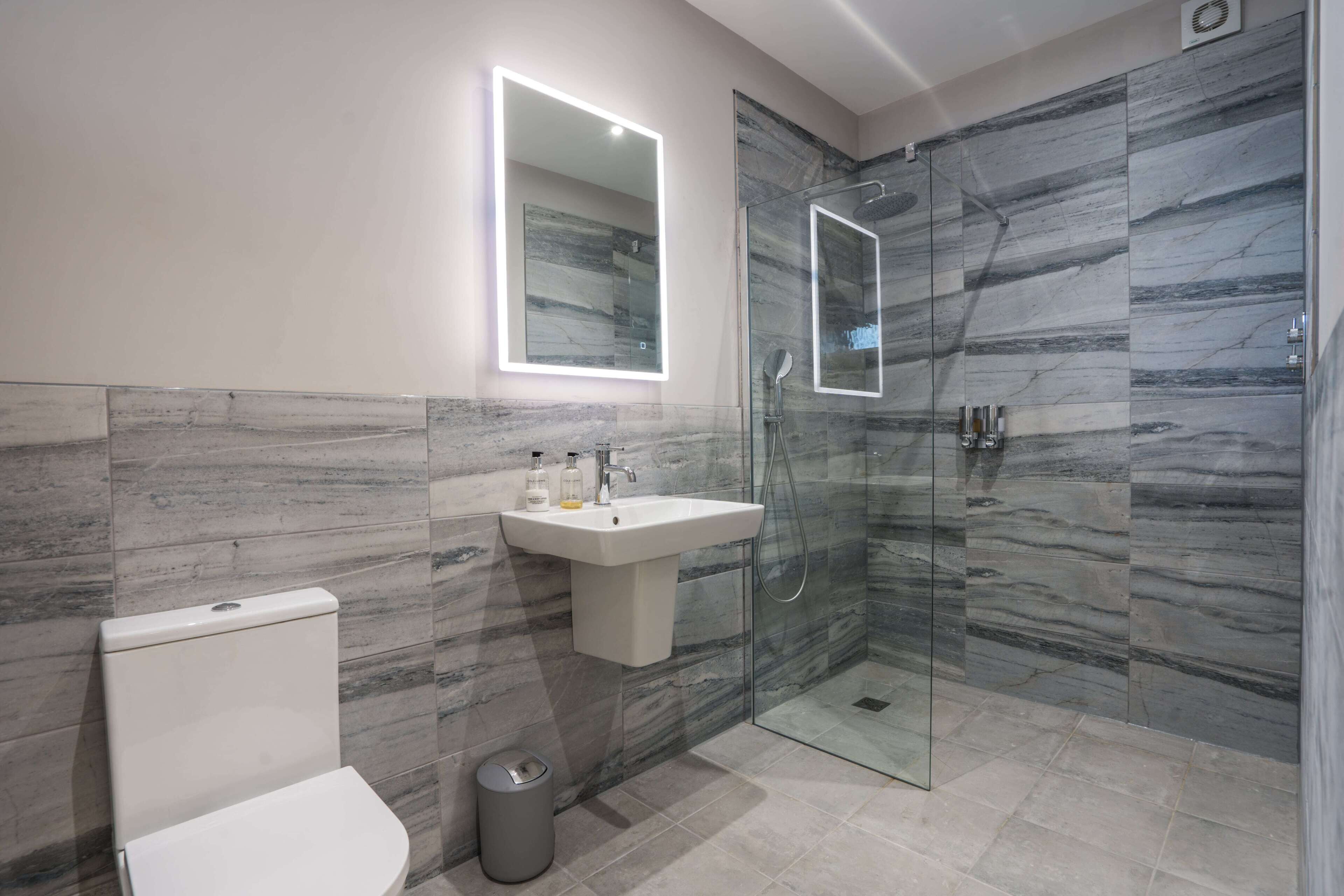 A modern bathroom with a toilet, sink, and glass-enclosed shower.