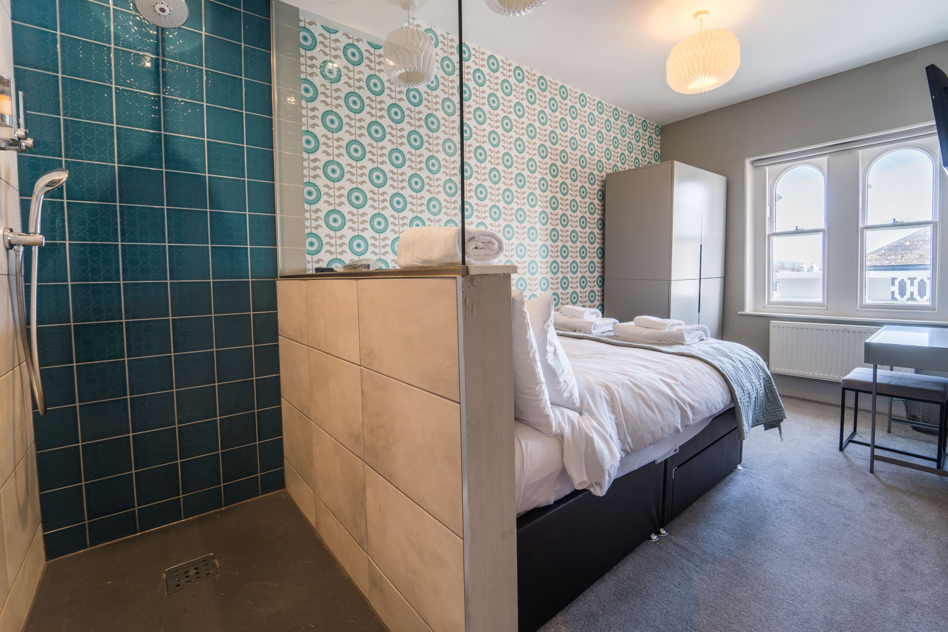 Un dormitorio con cama, ducha, ventana y escritorio.