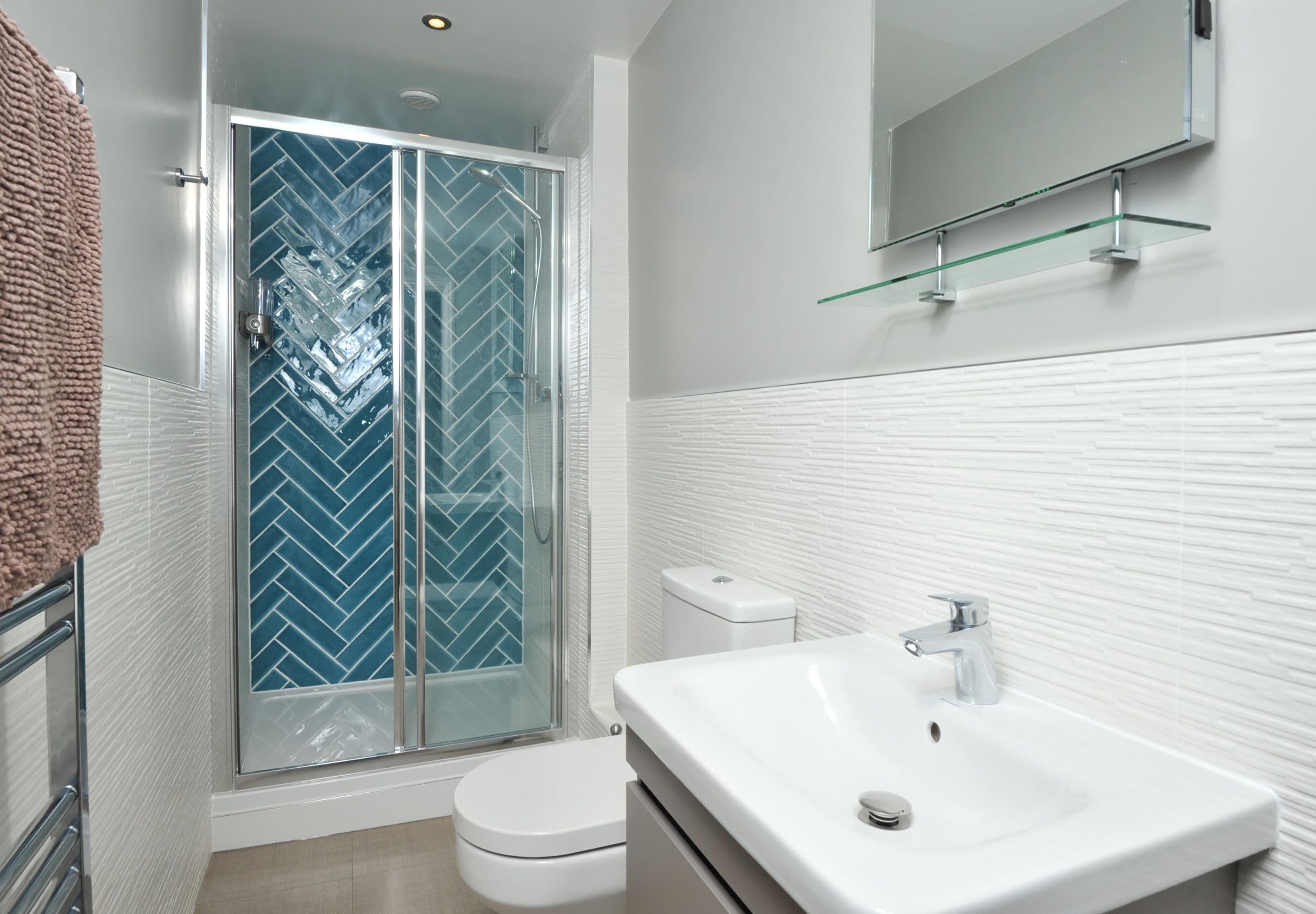 Un baño moderno con cabina de ducha de vidrio, inodoro blanco y lavamanos blanco con espejo arriba.