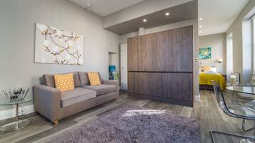 A modern living room with a grey sofa, a purple rug, and a wooden cabinet.