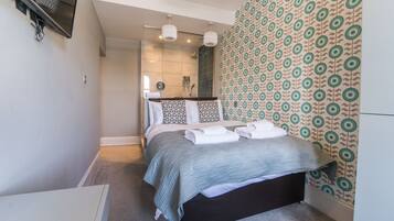 A modern bedroom with a bed, a shower area, and patterned wallpaper.