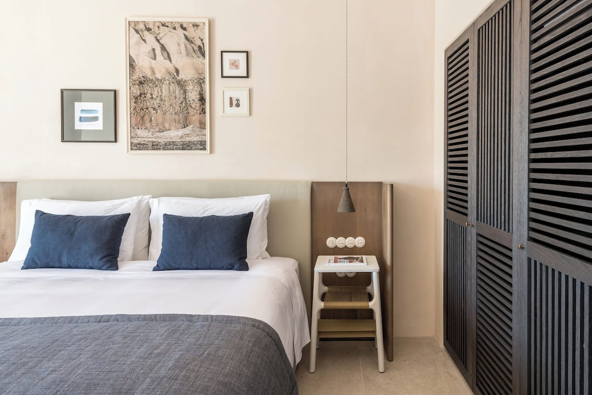 Un dormitorio ordenado con cama, mesita de noche y cuadro en la pared.